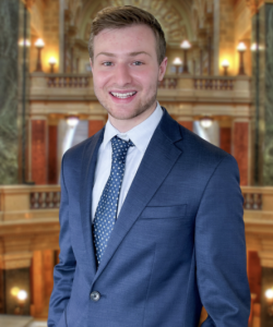 A man in a blue suit jacket smiling. 